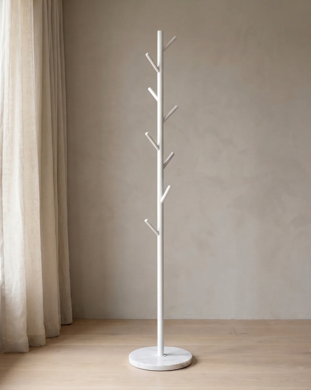 White version of the branch-style rack with a round marble-look base, standing empty beside a linen curtain 2