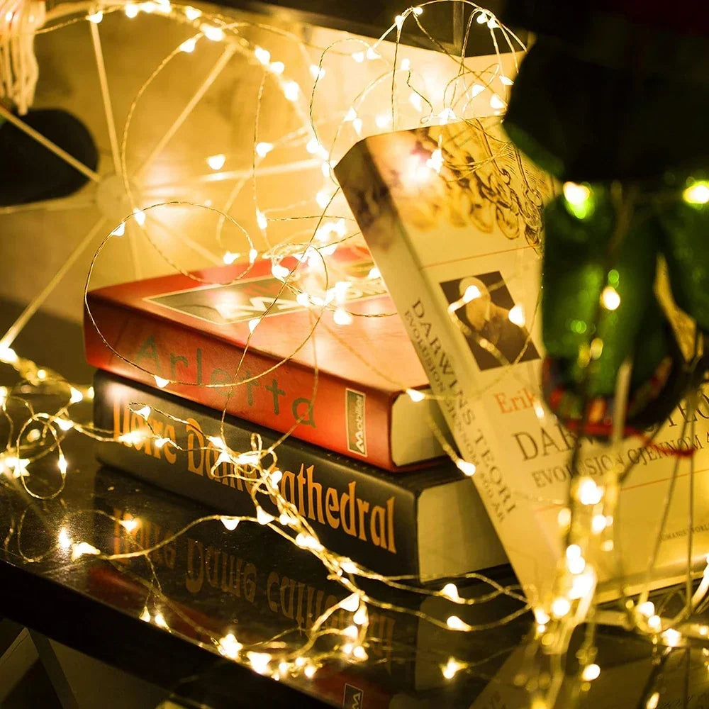 Warm white fairy lights draped around a stack of books on a dark glossy table 2