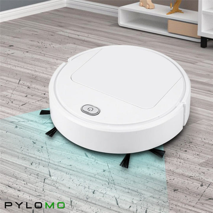 White robot vacuum on a gray plank floor in a living room, its side brushes sweeping a cleaned path 3