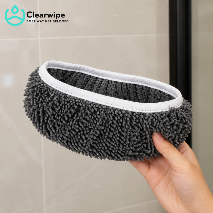 Hand holding a gray chenille mop pad with white elastic edging in front of beige bathroom tiles.