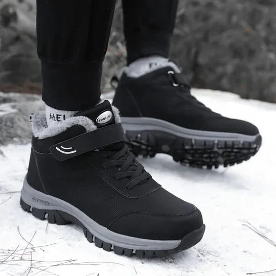 Person wearing black fleece-lined boots with strap closure while standing on snow 4