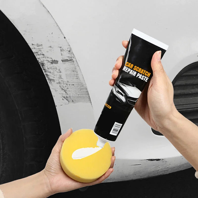 Close-up of hands squeezing white paste from the black tube onto a round yellow sponge, with a scuffed white car panel behind. 2