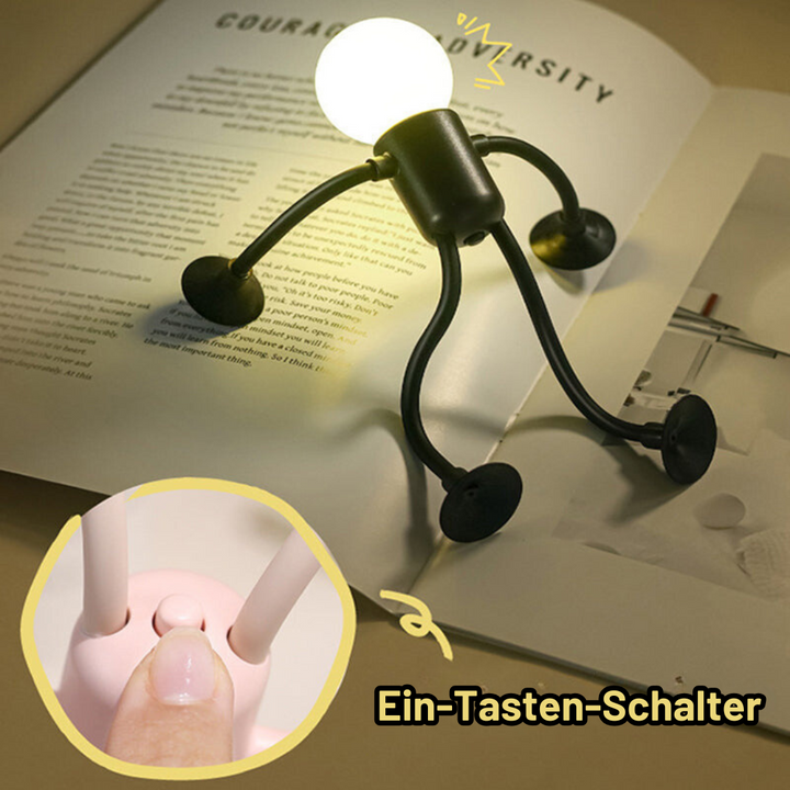 Black figure lamp sitting on an open book as a reading light, with a close-up of a finger pressing the pink lamp's button.