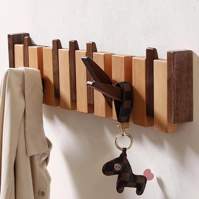 Close view of the rack with a beige jacket on one end and a checkered leather horse keychain on a folded-out hook.