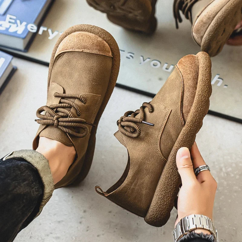 Khaki lace-up shoes seen from above, one worn and one held in hand 2