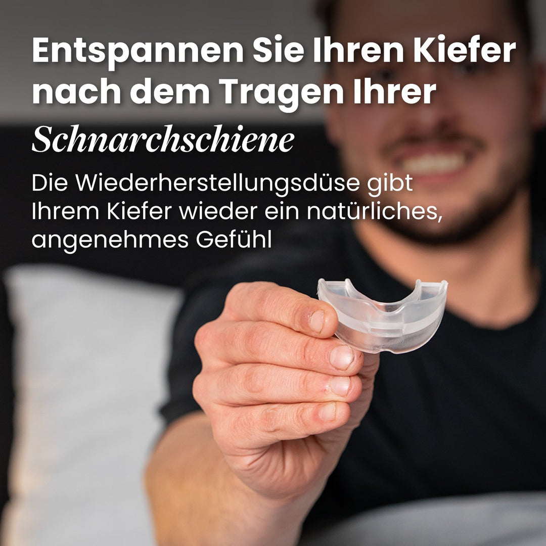 Smiling man holding out the clear recovery mouthpiece on a bed.