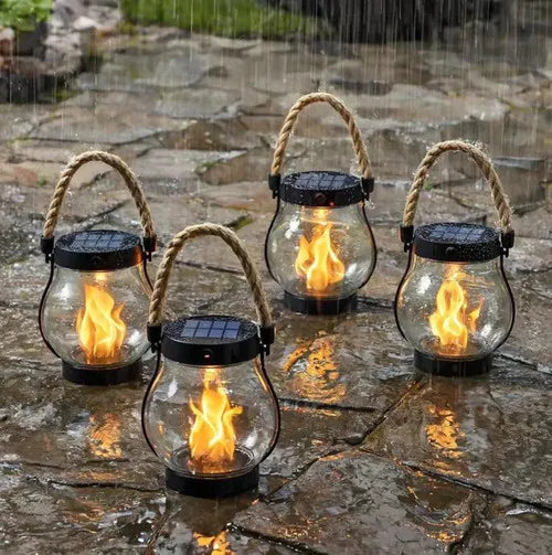 Four rope-handled lanterns with flickering flames sitting on wet stone pavers in the rain 2
