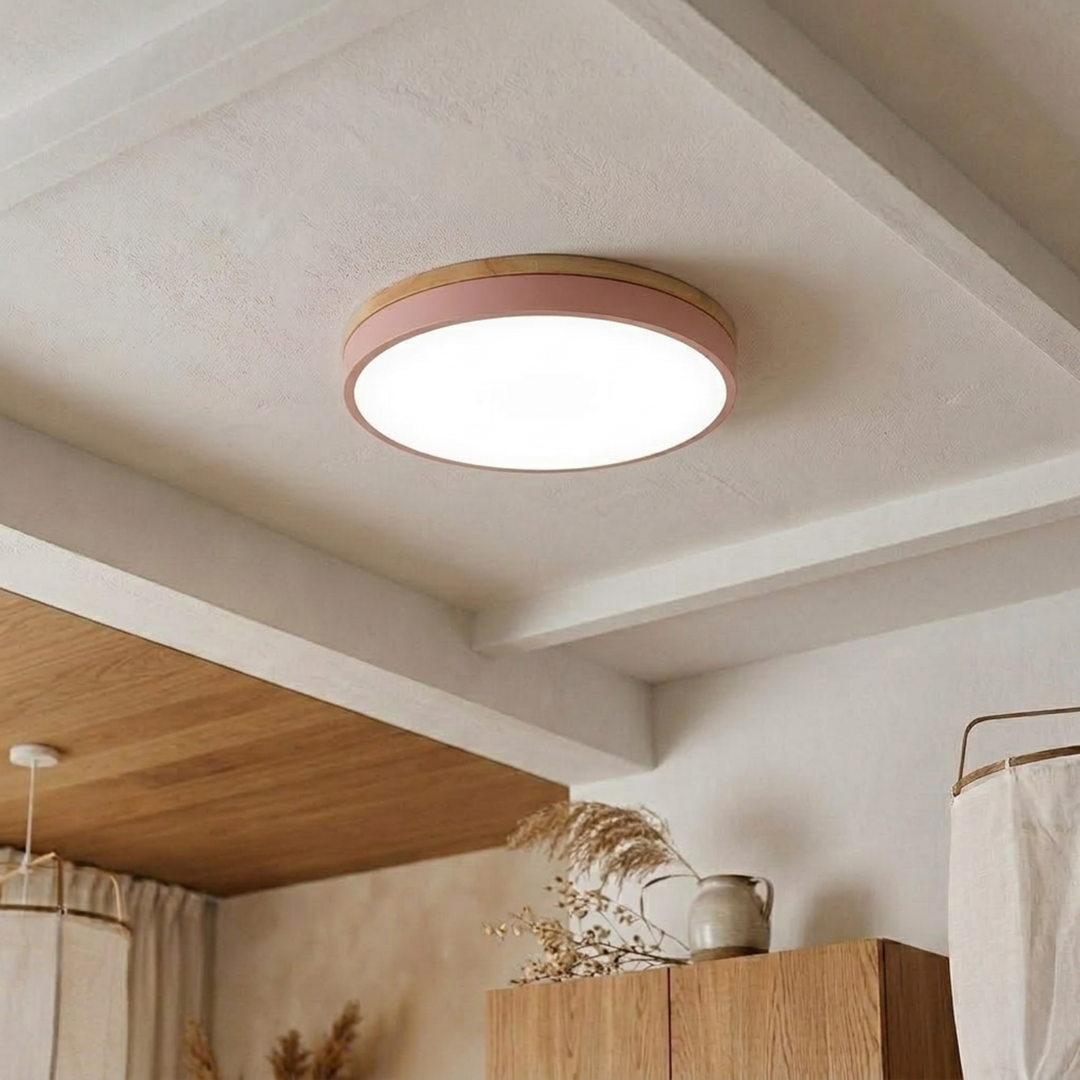 Pink disc ceiling light with a wood-grain top band shining bright cool white on a beamed plaster ceiling. 20