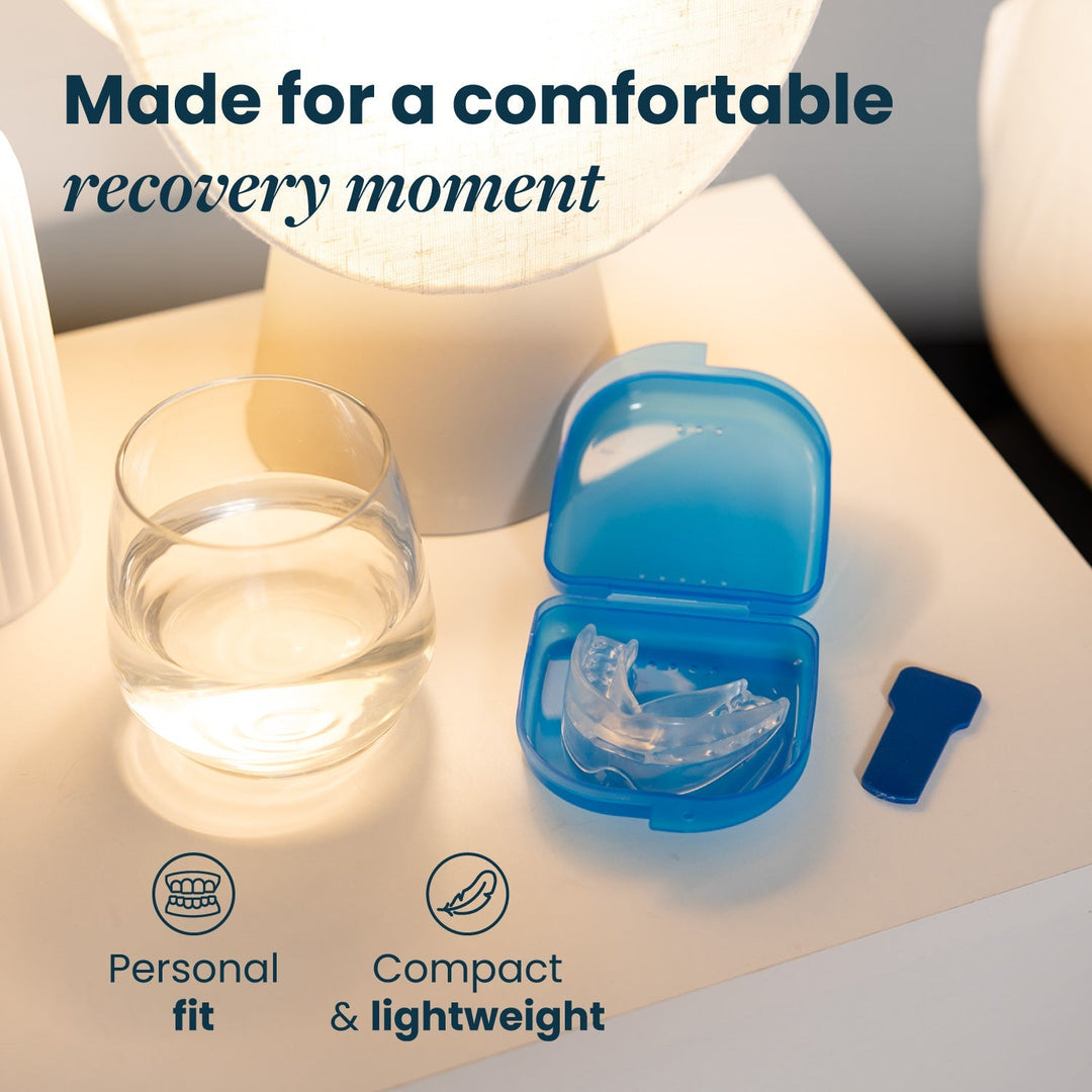 Clear mouthpiece resting in an open blue storage case on a bedside table next to a glass of water and a small blue tab. 22