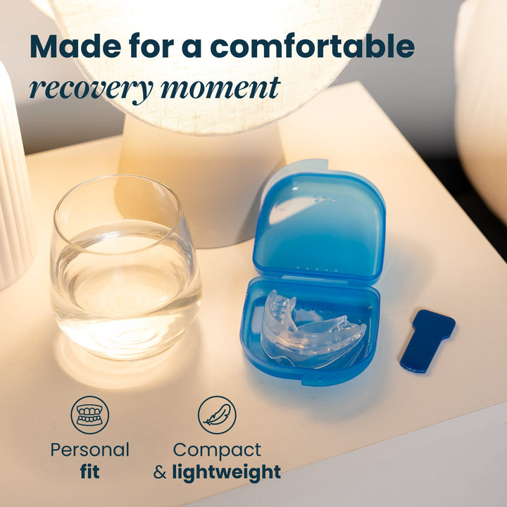 Clear mouthpiece resting in an open blue storage case on a bedside table next to a glass of water and a small blue tab. 22