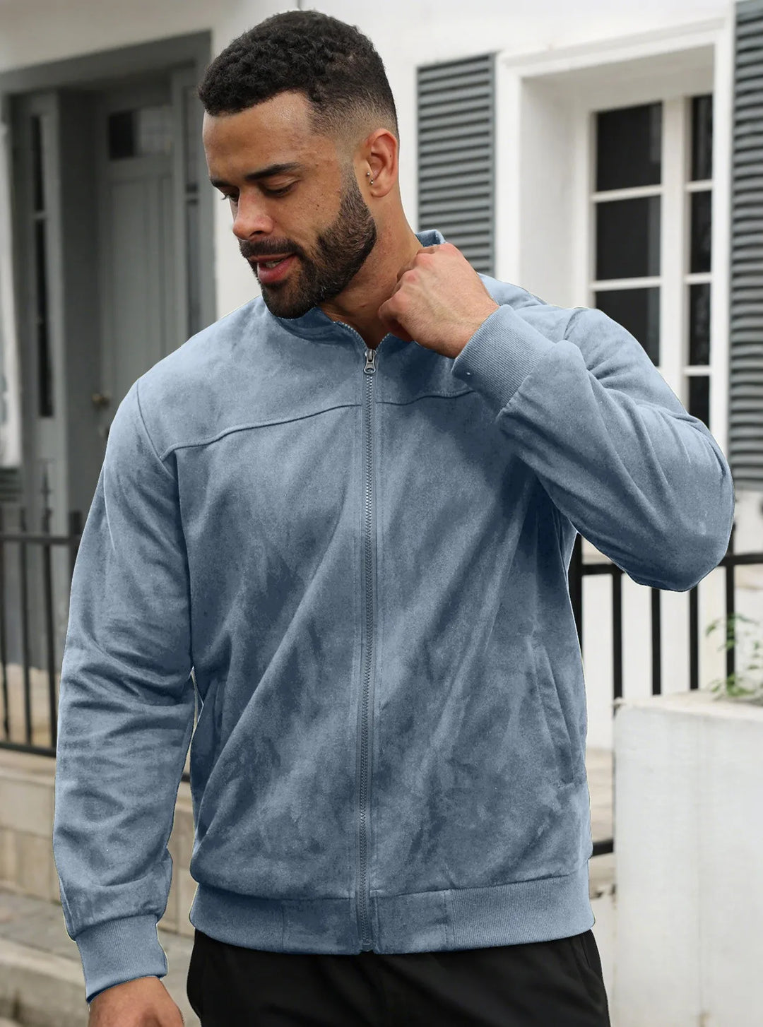 Man wearing slate blue suede-look zip-up jacket outdoors, front view, hand raised to his collar 30