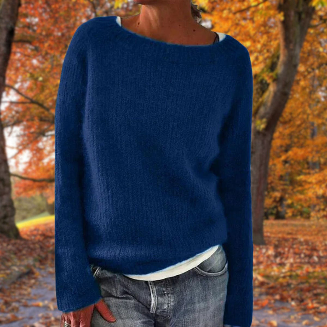 Navy blue knit sweater with long sleeves, worn over a white tee and gray jeans among fall foliage 3