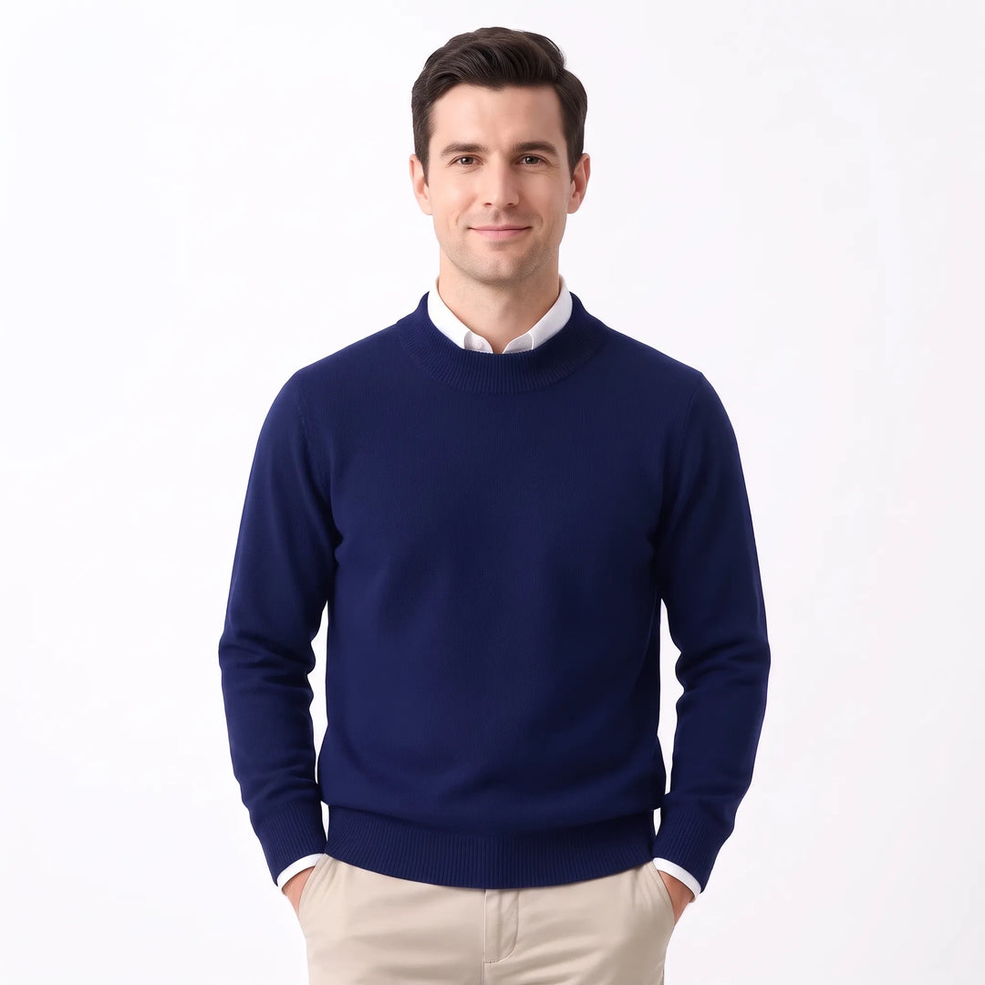 Man wearing the navy sweater over a white collared shirt with khaki pants, hands in pockets 32