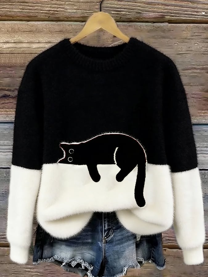 Black and white fuzzy colorblock sweater with a black cat lounging on the white section, hanging in front of weathered wood. 6