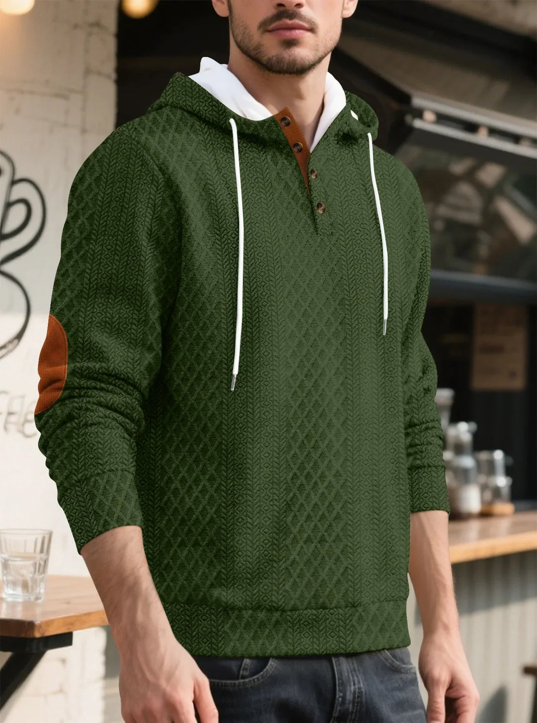 Angled view of the olive green textured hoodie worn by a man at a cafe counter 34