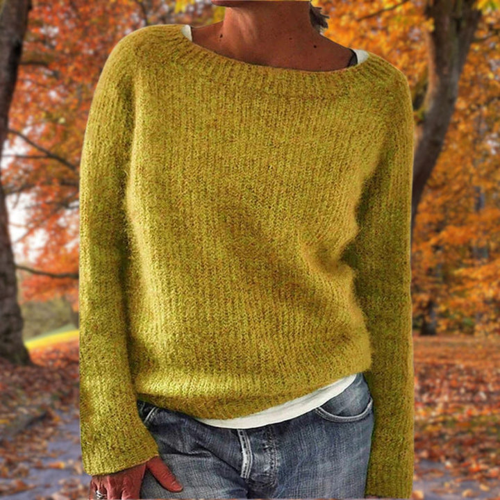 Mustard yellow knit sweater with a round neck, worn over a white tee and jeans among autumn trees 1