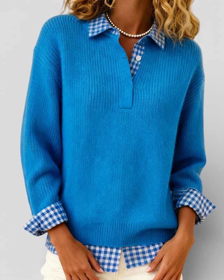 Blue knit sweater detail with a pearl necklace and gingham shirt collar and cuffs visible.