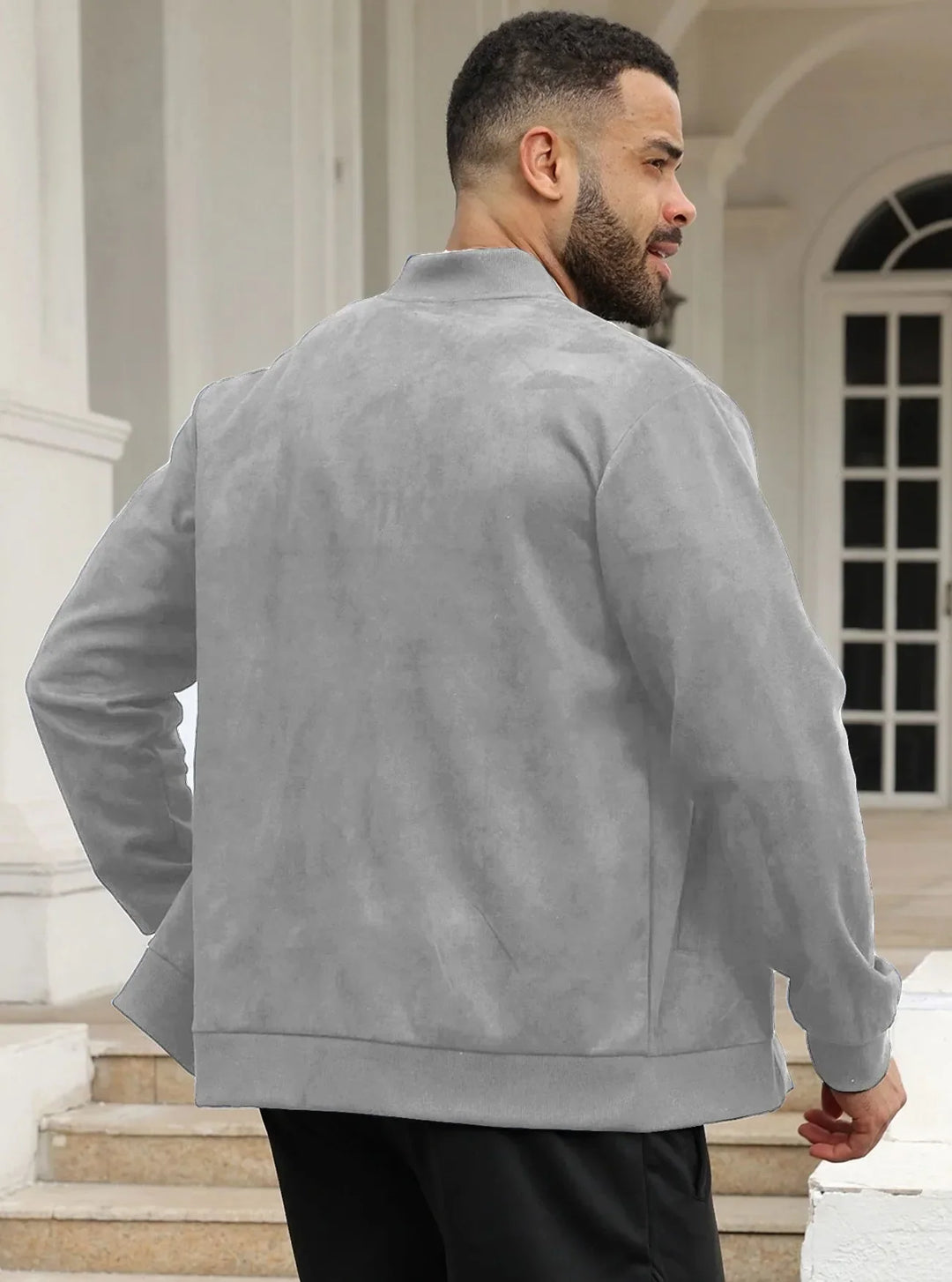Man in light gray suede-look bomber jacket seen from behind, standing on steps by white columns 35