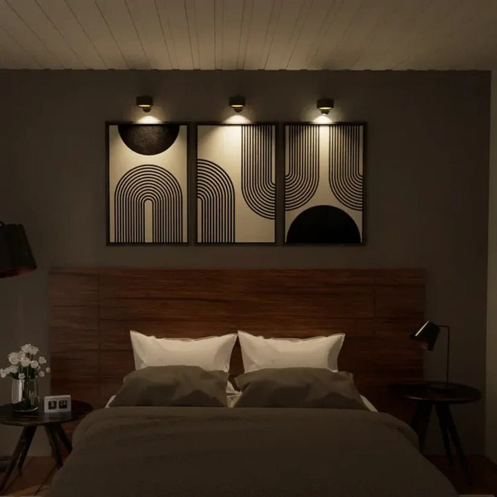 Black wireless LED wall lights above a headboard in a bedroom.