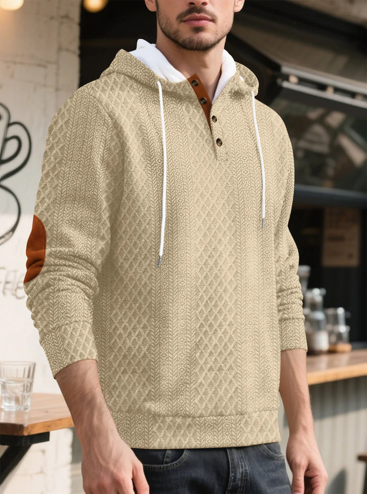 Angled view of the beige textured hoodie worn by a man at a cafe counter 36