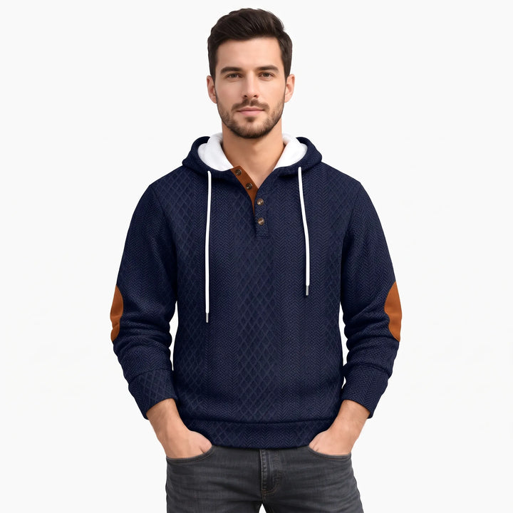 Studio shot of a man in the navy blue textured hoodie with hands in pockets 37