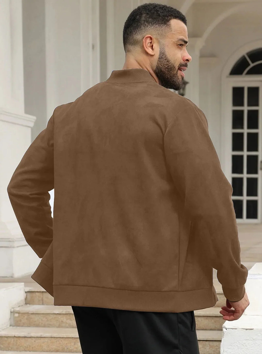 Man in brown suede-look bomber jacket seen from behind, standing on steps by white columns 39