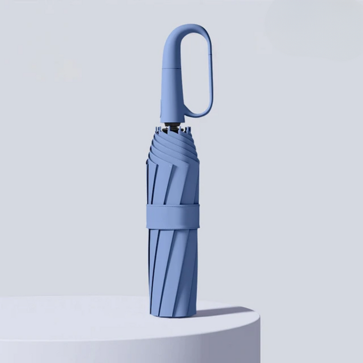 Closed folding umbrella in Blue with an oval hook handle and fabric strap.