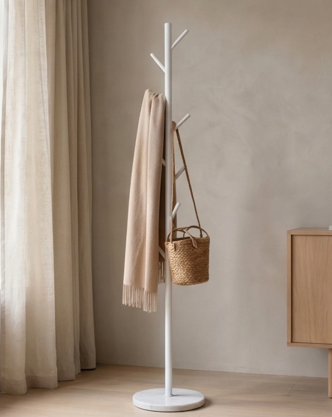 White rack holding a beige fringed scarf and a woven straw bag, next to a wooden sideboard 3
