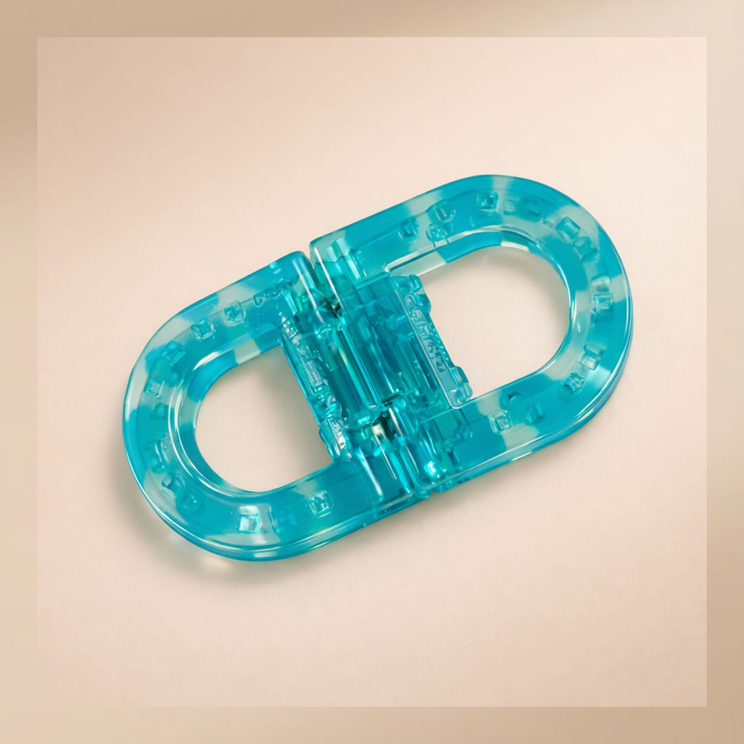 Flat Grip Magnetic Hair Clip in translucent turquoise, shown from above on a peach background.