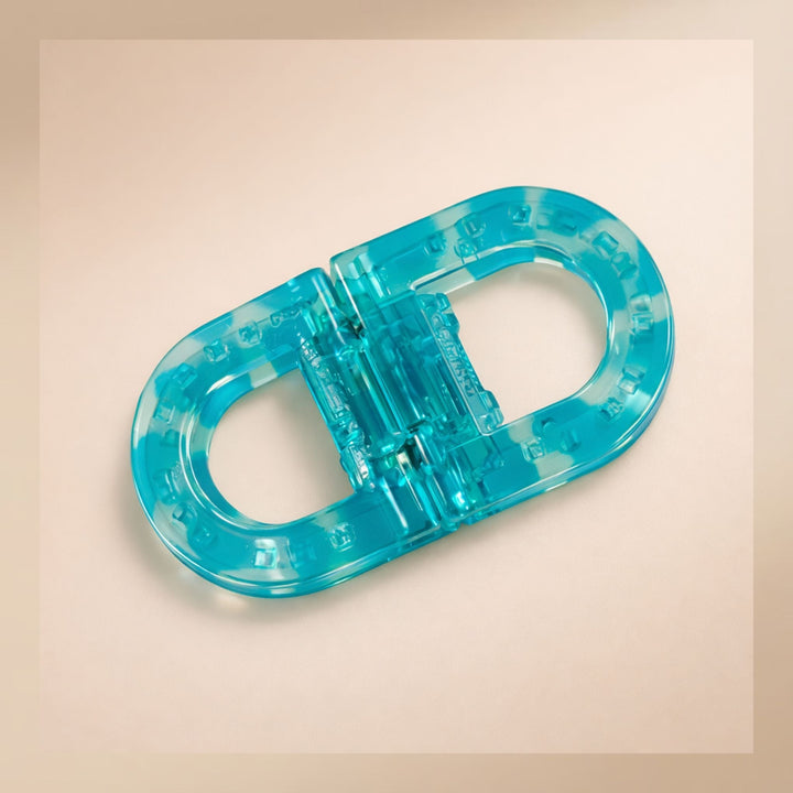 Flat Grip Magnetic Hair Clip in translucent turquoise, shown from above on a peach background.