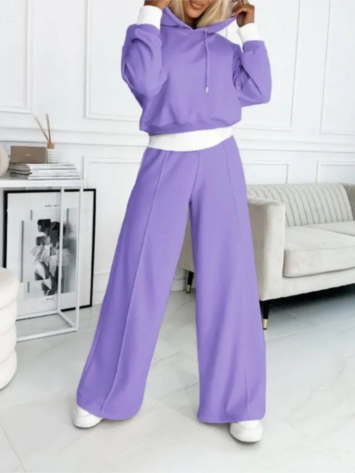 Model in a lavender hoodie and wide-leg pants with white cuffs and waistband, standing in a living room 3