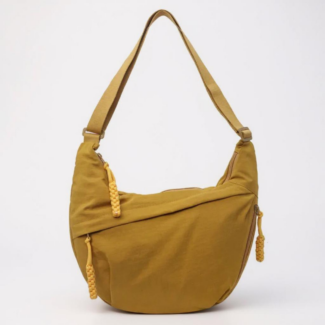 Mustard yellow nylon shoulder bag with adjustable strap and braided zipper pulls, detail.