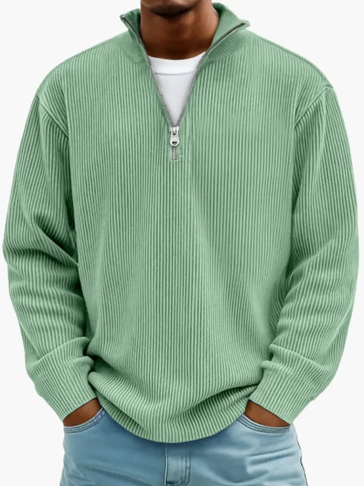 Man wearing the ribbed quarter-zip sweater in soft mint green over a white tee, hands in jeans pockets.