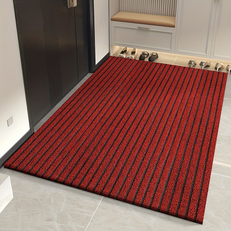 Grey striped doormat with dark grooves laid in a hallway beside a dark door.