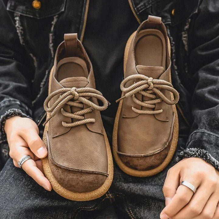 Pair of light brown lace-up shoes held on a lap, showing insoles and heel tabs 3