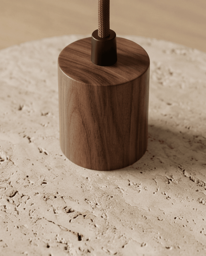 Travertine pendant light detail of the dark walnut-toned wood cylinder and braided cord.