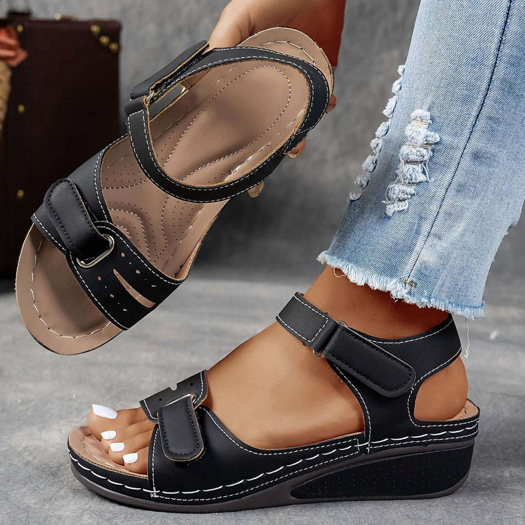 Black wedge sandal with white stitching and adjustable ankle and forefoot straps, with the insole visible. 4