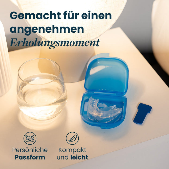Clear recovery mouthpiece in an open blue case next to a water glass and a blue tab.