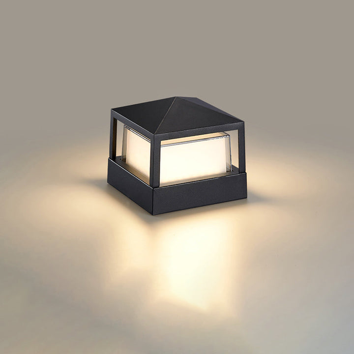 Square black lamp with a pyramid-shaped top and open frame, glowing warm white on a neutral background. 10