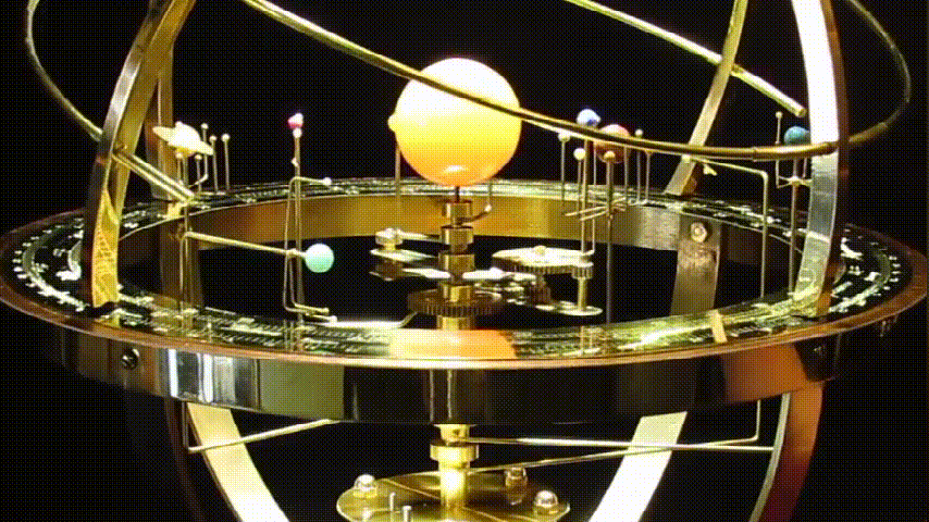 Brass orrery detail with the central sun and small planet spheres above the engraved zodiac ring.