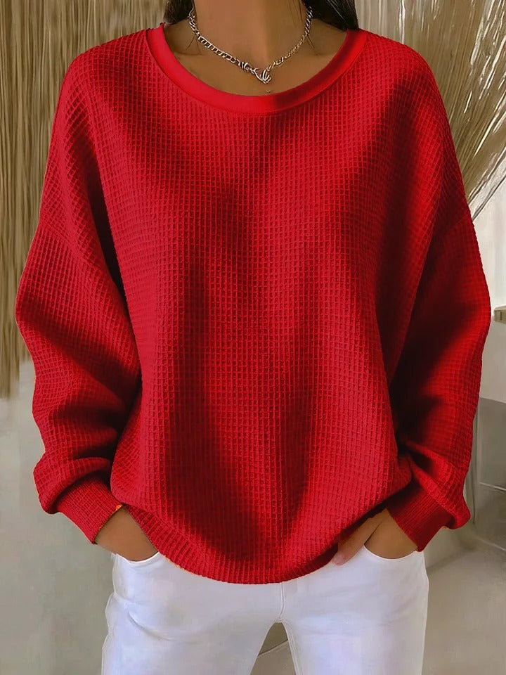 Red waffle-knit crew neck sweater with ribbed cuffs and hem and white pants.