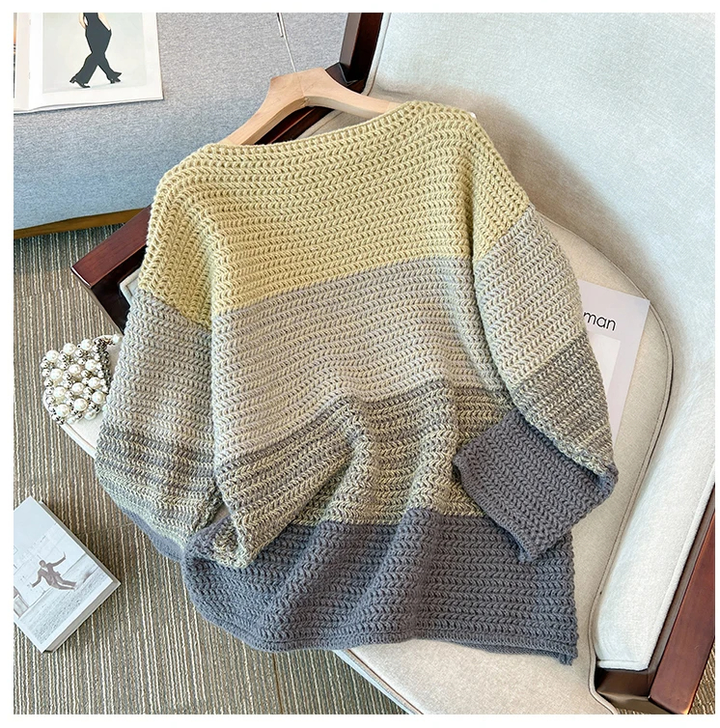 Gestrickter Pullover Damen, mehrfarbig, beige-grau, gemütlich, Herbstmode, auf Sofa drapiert.