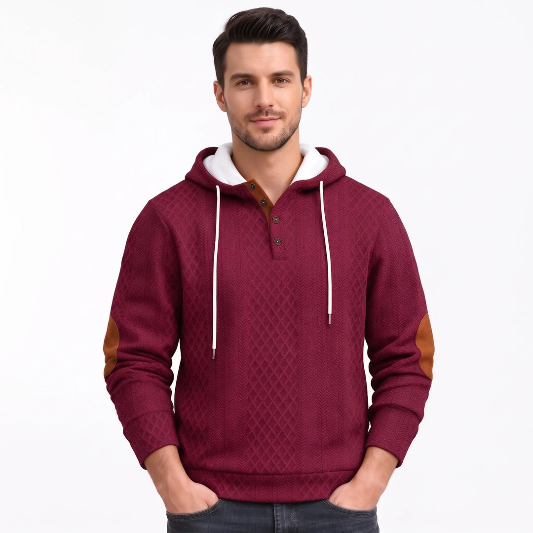 Studio shot of a man in the burgundy textured hoodie with hands in pockets 40