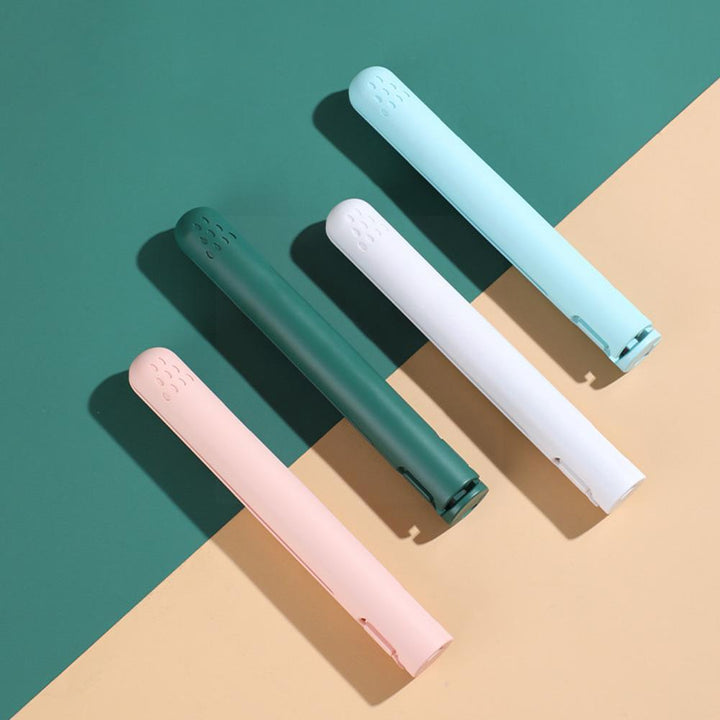 Four closed straighteners in pink, green, white and blue laid diagonally across a green and peach background 5
