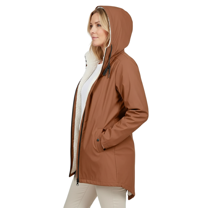 Side detail of a woman in the rust-brown jacket, hood up and unzipped, showing thick cream fleece lining and hand in pocket.