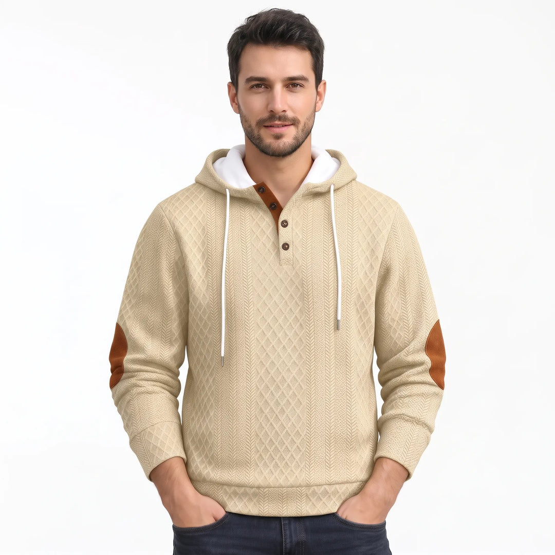 Man wearing beige diamond-textured hoodie with white drawstrings, brown button placket and brown elbow patches, standing with 44