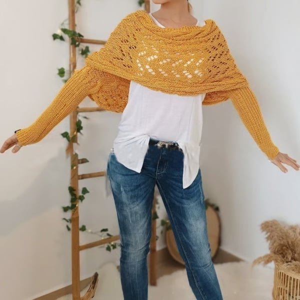 Woman wears the mustard-yellow lace-knit wrap with long ribbed sleeves over a white tee and jeans, arms stretched out to the sides. 22