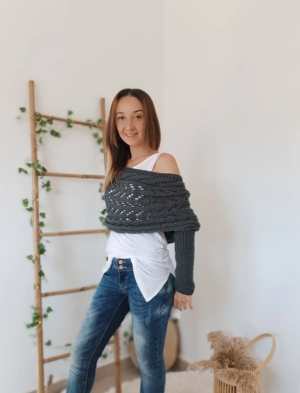 Side view of the gray wrap draped off the shoulder, with one long ribbed sleeve hanging down beside a ladder decorated with ivy. 4