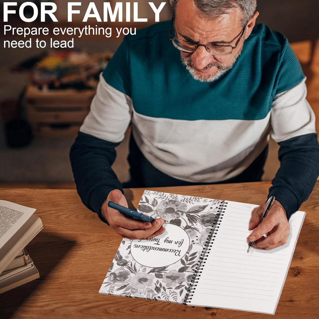 Older man with glasses holds a phone and writes by hand in the open planner on a desk 4