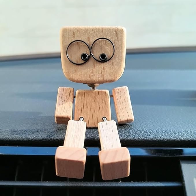 Light wooden figure with wire-ring googly eyes sits on a car dashboard, legs dangling over the edge 1